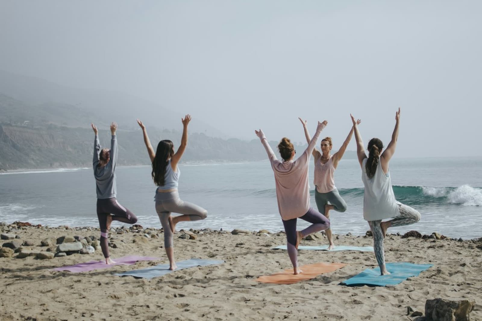 Fünf Frauen bei Yoga-Übungen am Strand